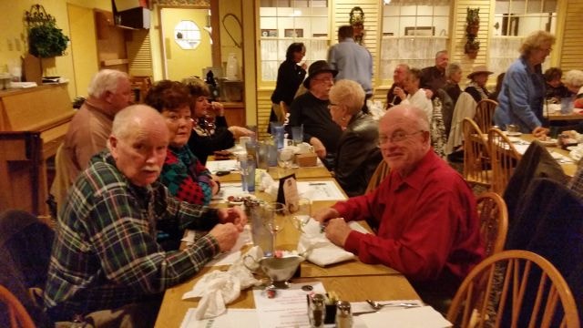 October 2015 Dinner — members seated at restaurant tables with man in red shirt prominent in foreground